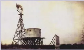 A black and white photo of a windmill and a water tower.