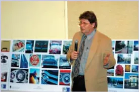 A photo of a person in a suit with a microphone with photos behind them.