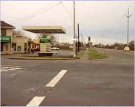 A photo of an intersection with a gas station in the background.