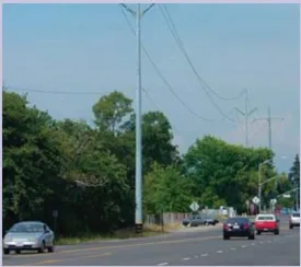 A photo of a road with cars driving and power lines overhead.
