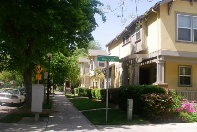A corner lot on a street with townhomes with mature growth trees.