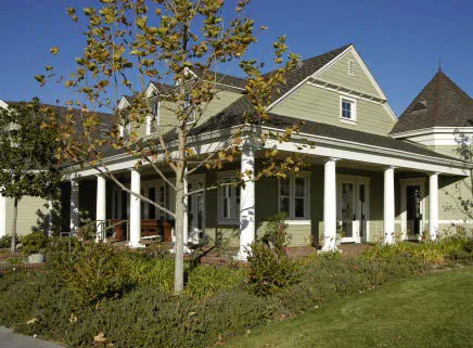 House with shrubs adjacent to a portico.