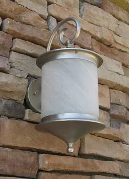 Silver light fixture on a wall with brick siding.