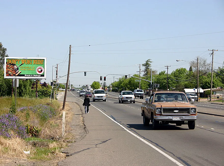 Pedestrian walking on the side of a road with no sidewalk.