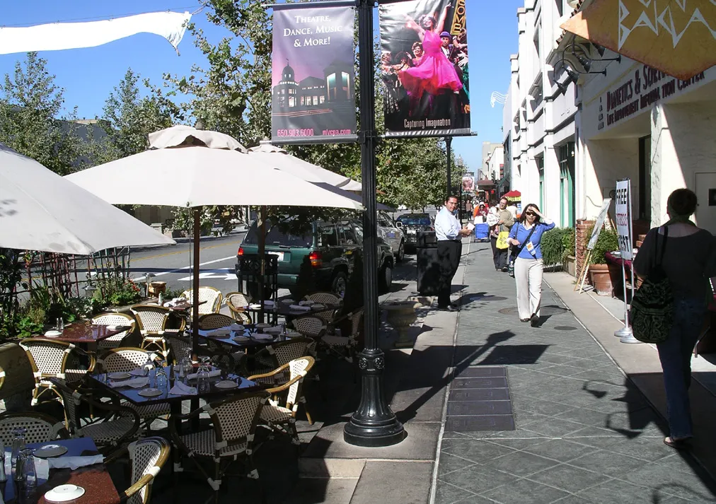 A commercial store front with wide sidewalks and seating areas.