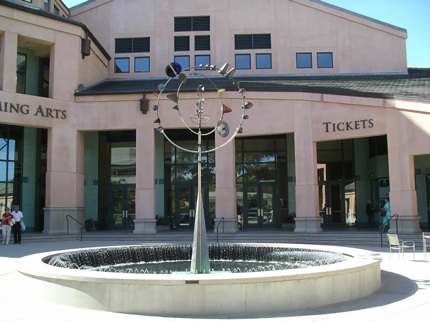 A water fountain at a building front with seating.