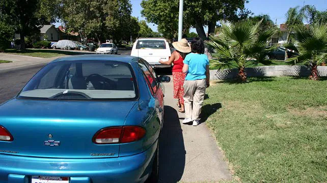 Car parked on the sidewalk in a residential neighborhood.