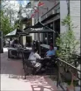 Two people sitting in the outdoor seating area of a restaurant.