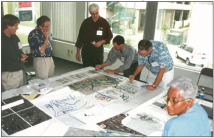 Six people looking over a table covered in maps and diagrams.