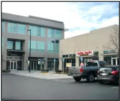 Multi-tenant retail store fronts viewed from the parking lot.