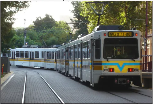 A light rail train running along the street with a sign that says Watt/I-80.
