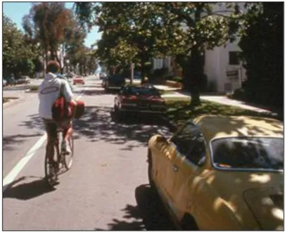 A person riding a bike next to parked cars.