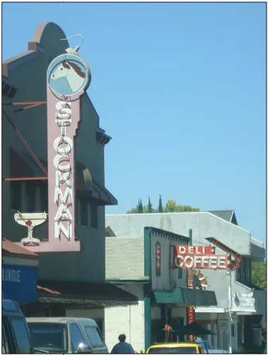 Storefronts that have two signs. One says "Deli Coffee," while the other says "Stockman" with an image of a horse above it.
