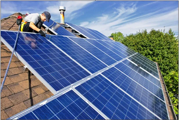 A man on a roof installing photovoltaic panels.