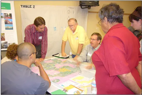Seven people gathered around a map on top of a table.
