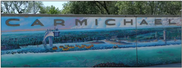 A mural of people rafting down a river with a sign that says "Carmichael."